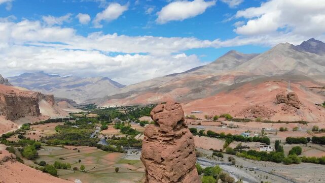 Drone orbiting a towering rock pillar in arid Ladakh landscape.