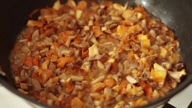 Close-Up of Chopped Chanterelle Mushrooms Frying in Skillet on Stove