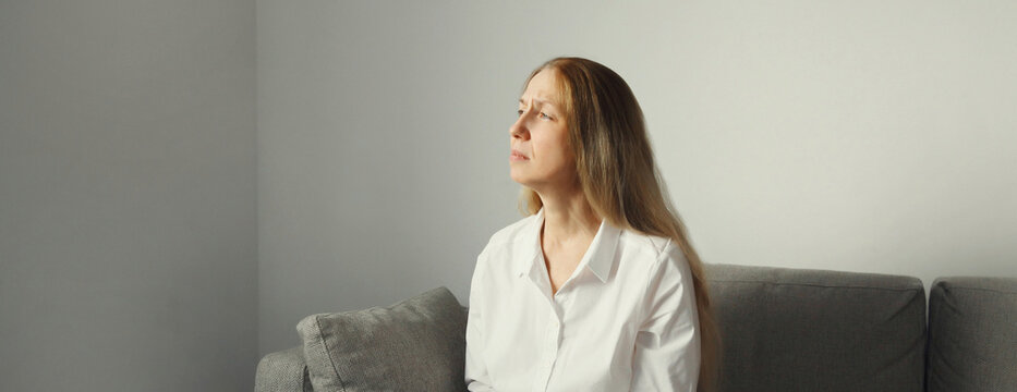 Pensive woman thinks looks out the window, thoughtful girl suffering from depression at home