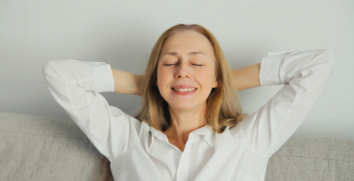 Happy relaxed young woman enjoying at home, satisfied girl sitting on the couch in living room