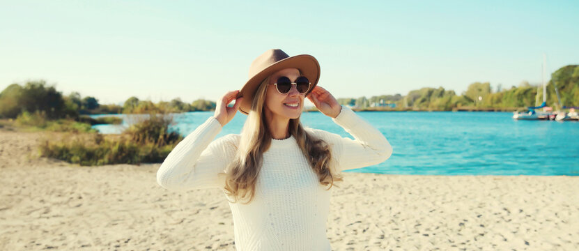 Stylish happy woman standing on beach, looking away, posing on sea coast background