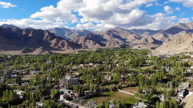 Cinematic aerial drone orbit shot capturing a sweeping panoramic view of Leh town in Ladakh, India. 