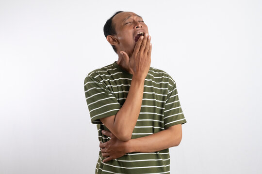 Young asian handsome man over isolated background yawning and covering wide open mouth with hand