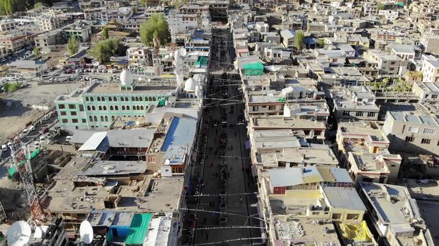 Aerial flight over Leh Main Bazaar tilting up to reveal Leh Palace in the backdrop of the high-altitude Himalayas
