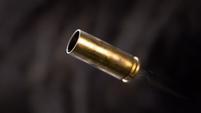 ejected. Single brass cartridge case ejected from an antique revolver, isolated on dark background. mobility guides, transit brochures, designed for mobility and urban transit guides.