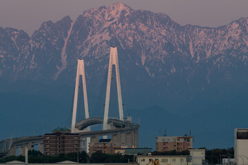 新湊大橋と夕日に染まる剱岳 © easterlily.photos