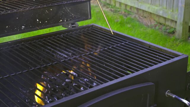 Empty outdoor barbecue grill with bright orange flames and fire rising from burning charcoal.