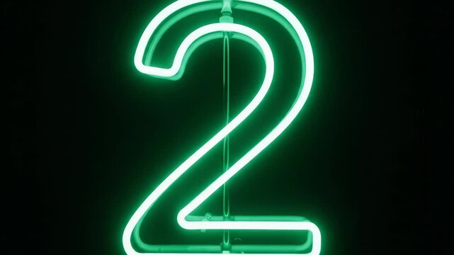 Glowing green neon number two sign isolated on a dark black background for countdown or ranking.