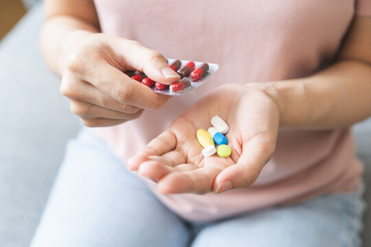 Sick ill asian young woman, girl hand taking tablet pill capsule out from blister pack, painkiller medicine from stomach pain, head ache, pain for treatment, take drug or vitamin at home, health care.