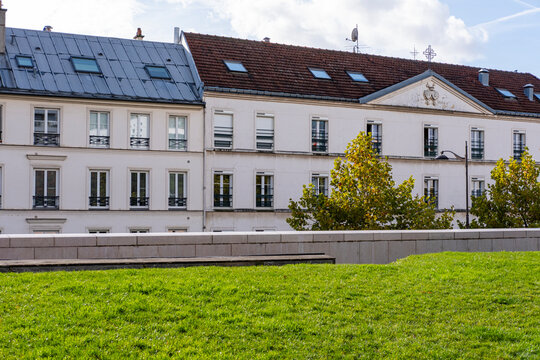 Open lawn and trees sit before historic buildings near Paris Rive Gauche, contrasting park landscape, residential architecture and urban green space