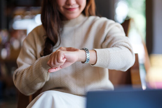 Closeup image of a woman checking time and pointing finger at a watch