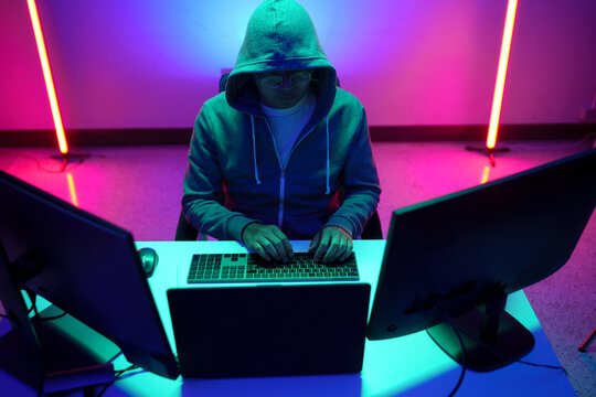 Hacker in Hoodie Typing at Multi Monitor Computer Setup