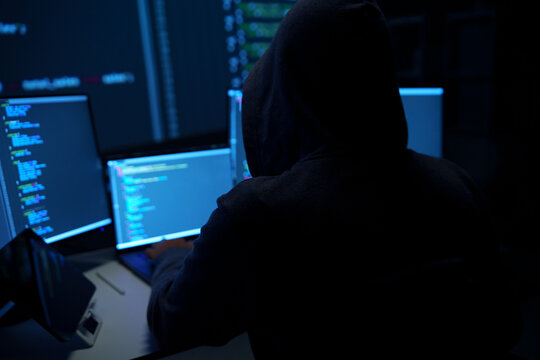 Hacker in Hoodie Working at Multiple Computer Monitors