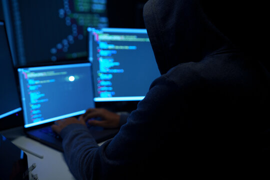 Hacker Working on Laptop with Code on Dark Screens