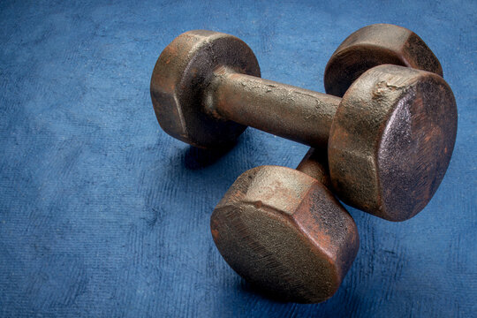 old rusty dumbbells on textured handmade bark paper with a copy space
