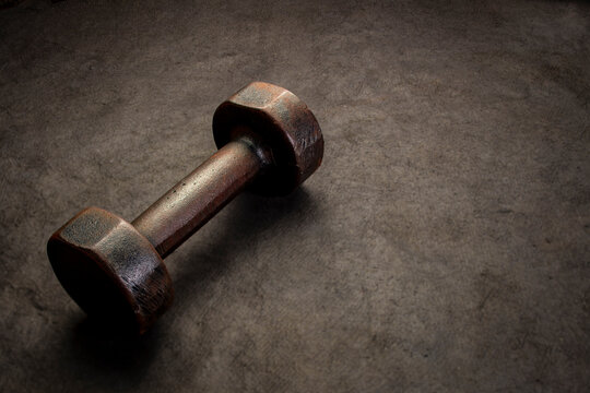old rusty dumbbell on textured handmade bark paper with a copy space