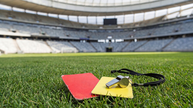 Referee cards, classic soccer ball and whistle on the green field in soccer stadium. ready for game in the midfield
