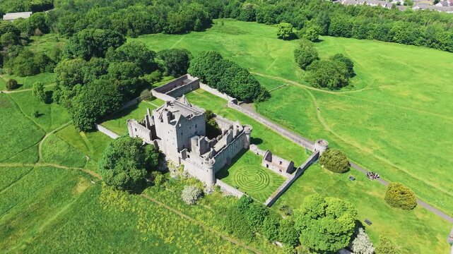 Cinematic aerial drone orbiting shot of the historic medieval Craigmillar Castle in Edinburgh, Scotland. Beautiful ancient stone fortress tracking flight on a sunny summer day