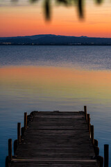 Obraz premium beautiful sunset on a lake with mountains in the background and wooden pier in the foreground