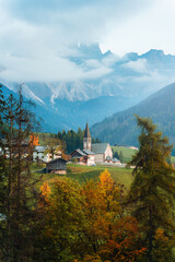 Obraz premium Scenic Alpine Village with Stone Church of St Magdalena and Dolomites Mountain in Autumn Season Italy