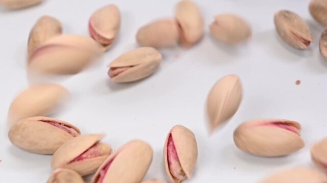 pistachios falling on white surface, slow motion
