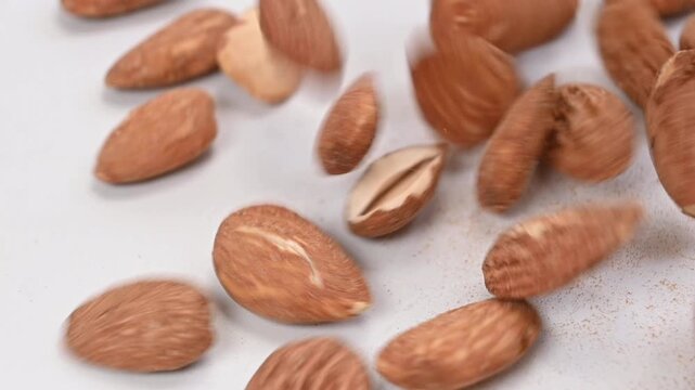 almonds falling on white surface, slow motion