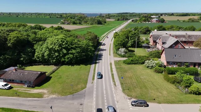 Aerial view of rural landscape road with cars passing fields and farms, Denmark