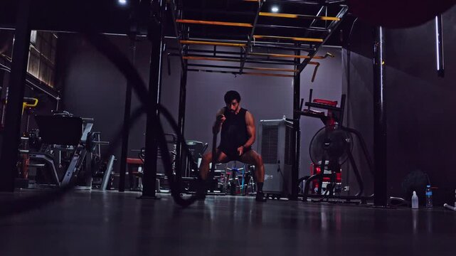 Fitness gym workout athlete kettlebell strength training exercise man male in dark modern gym interior performing kettlebell and battle rope strength training workout for endurance power focus