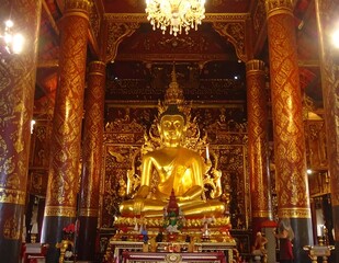 Fototapeta premium Ornate Golden Buddha Statue Sitting in Elaborate Temple Interior