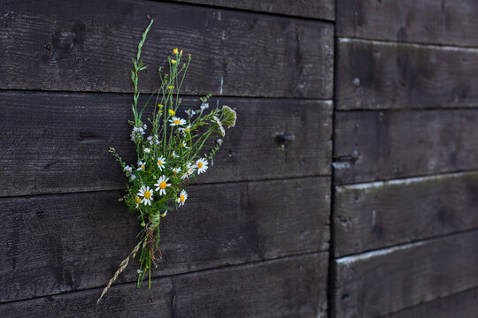 Kleines Blumengesteck auf schwarzer Holzwand.