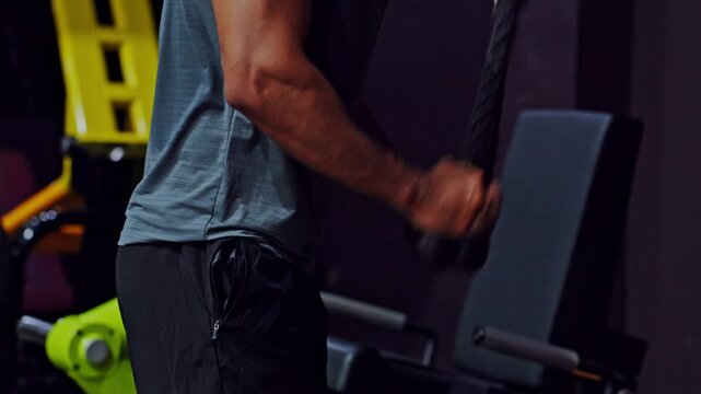 Strength training gym triceps cable workout athlete fitness muscle arm exercise, closeup view of athletic man using cable machine for triceps workout, muscular arm flexing with focused effort indoor