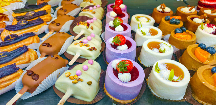 Selection of assorted cakes, eclairs and sweet desserts on a display tray. Pastry shop showcase with chocolate and fruit treats. Delicious food and snack for celebration and cafe