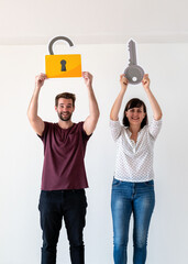 Obraz premium Two people holding a lock and key cutout, smiling in a bright room.