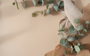 Eucalyptus branches and burlap fabric on a light beige background © Sumon