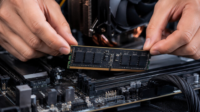 Hands installing RAM module on computer motherboard
