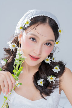 Extreme close up of Asian woman face framing with daisy flowers for botanical cosmetics skincare marketing campaign organic treatment concept holistic beauty wellness softness editorial