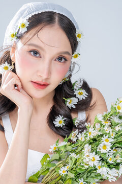 Extreme close up of Asian woman face framing with daisy flowers for botanical cosmetics skincare marketing campaign organic treatment concept holistic beauty wellness softness editorial