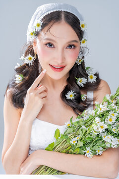 Extreme close up of Asian woman face framing with daisy flowers for botanical cosmetics skincare marketing campaign organic treatment concept holistic beauty wellness softness editorial