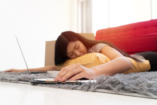Tired of Work: A woman, exhausted from her workload, lies face down on a cozy rug, laptop and phone in the frame, reflecting the everyday struggles of modern life.