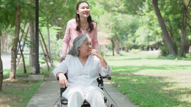 Asian careful caregiver or nurse taking care of the patient in a wheelchair. Concept of happy retirement with care from a caregiver and Savings and senior health insurance, a Happy family