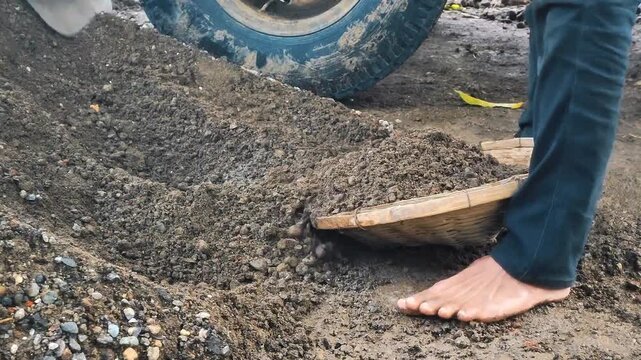 Shoveling sand into traditional sieve