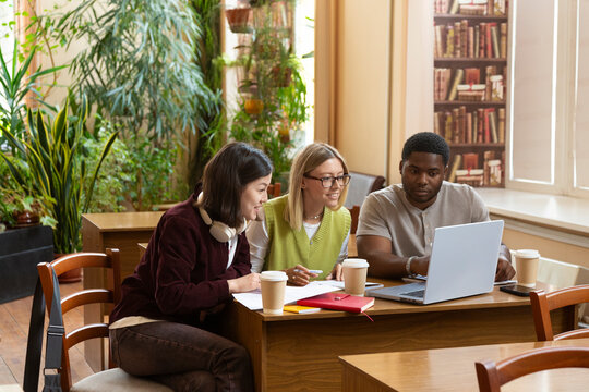 Diverse students collaborating on a laptop in library