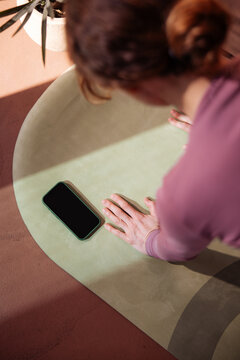 Woman Doing Yoga On Mat With Phone Nearby