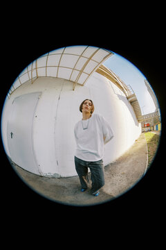 Person Stands by a White Wall in an Urban Area During Daylight