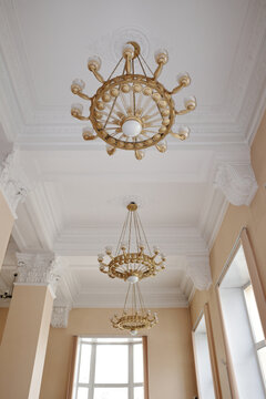 Chandeliers illuminating ornate ceiling in academic library hall