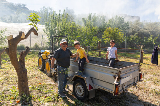 Grandpa and grandchildren enjoying farm activities with tractor
