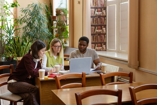 Diverse students collaborating on a laptop in library