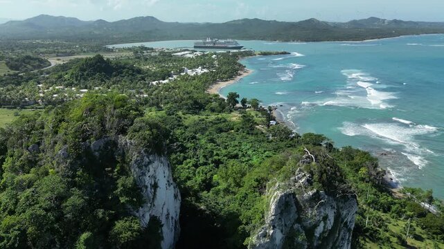 Aerial footage of Maimon Bay with crystal blue waters, tropical vegetation, coastal resort area, cruise harbor and panoramic mountain scenery.