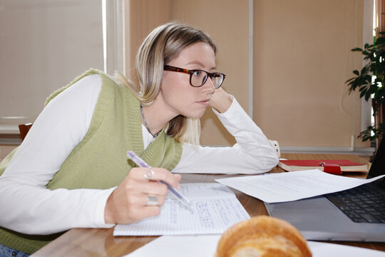 Person studying diligently at library desk with laptop