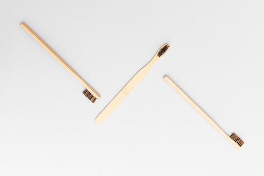 Three bamboo toothbrushes arranged diagonally in zigzag pattern on gray background